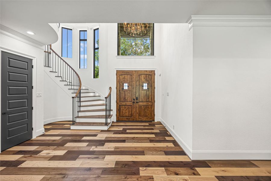 Stunning grand entry with soaring ceilings, abundant natural light, custom doors, and an elegant curved staircase Stunning grand entry with soaring ceilings, abundant natural light, custom doors, and an elegant curved staircase