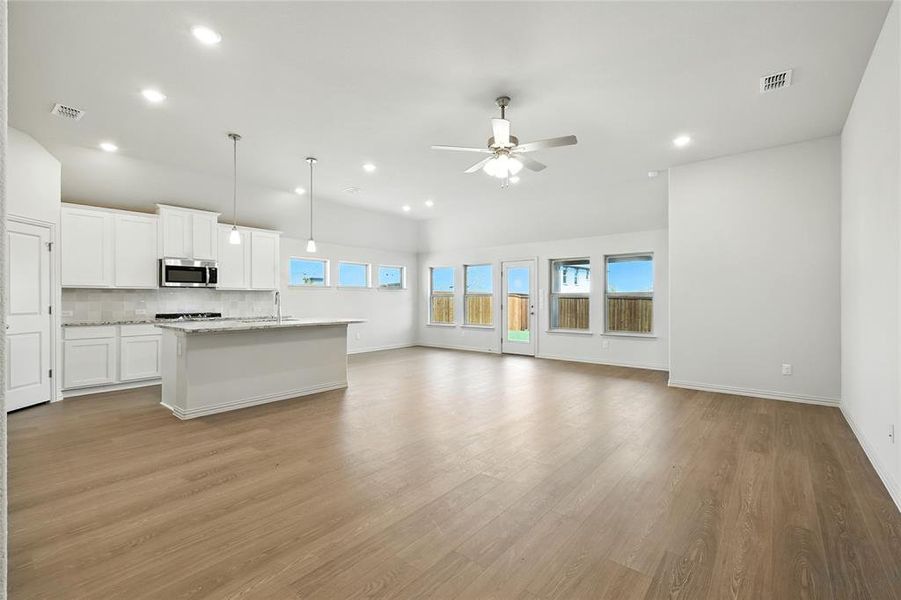 Kitchen with white cabinets, a kitchen island with sink, backsplash, pendant lighting, and light wood-type flooring Kitchen with white cabinets, a kitchen island with sink, backsplash, pendant lighting, and light wood-type flooring