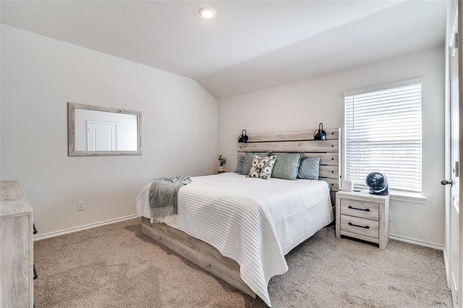 Carpeted bedroom featuring vaulted ceiling and baseboards