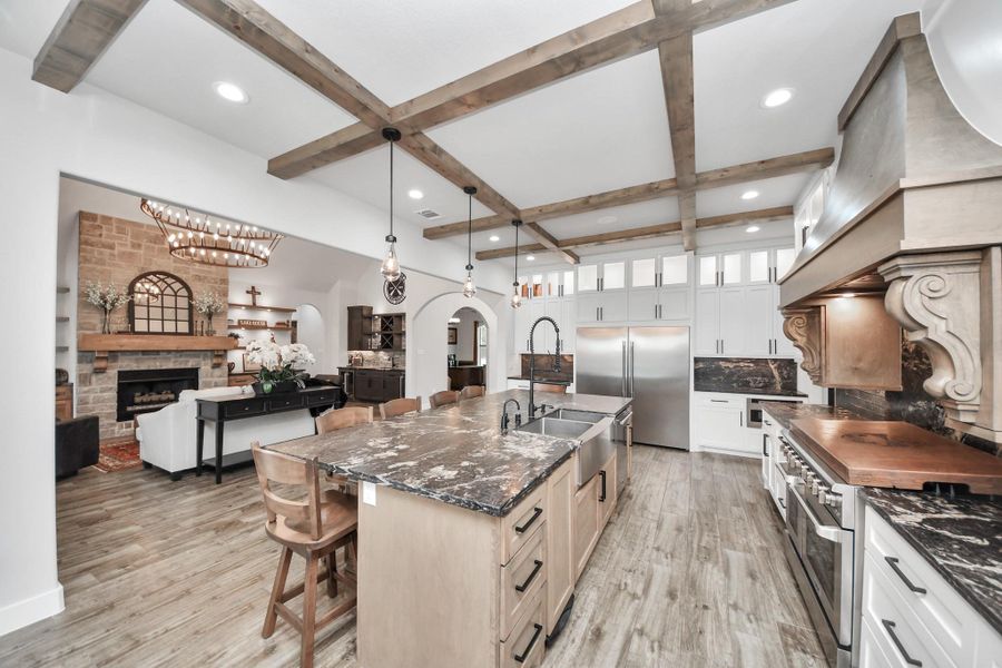 Stunning kitchen with rustic wood beams, marble countertops, and a spacious island, seamlessly flowing into a cozy living area with a stone fireplace.
