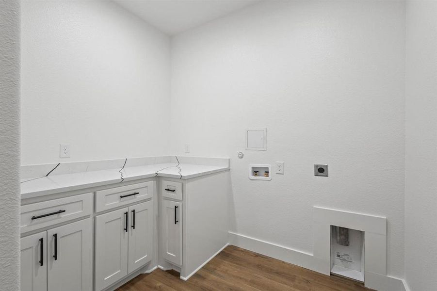 Washroom with dark wood-type flooring, washer hookup, cabinets, and electric dryer hookup