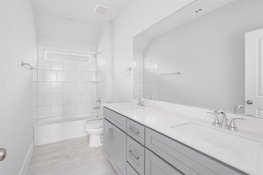 Bathroom with visible vents, a sink, toilet, and double vanity