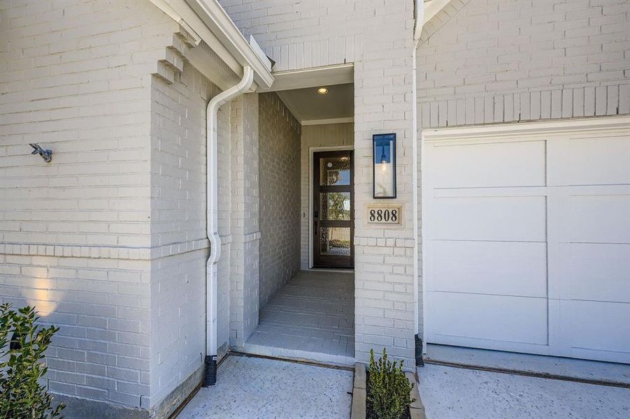 Property entrance with brick siding and a garage Property entrance with brick siding and a garage