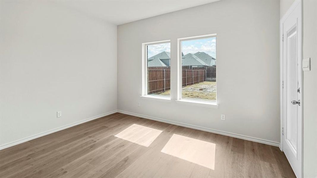 This room features light-colored walls, wood-look flooring, and natural light from two windows