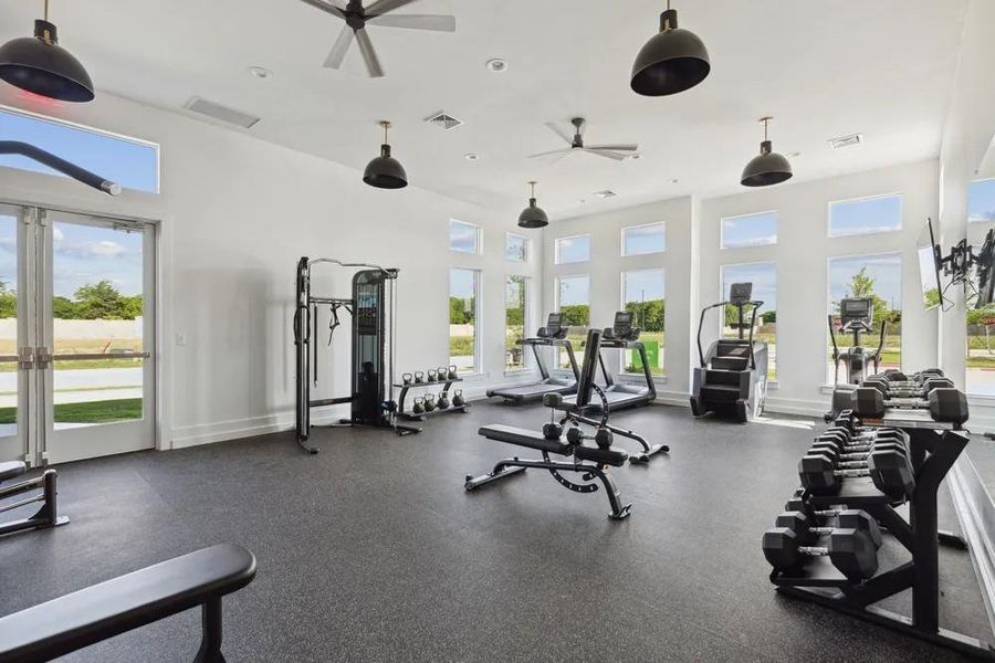 Workout area with ceiling fan, a high ceiling, and baseboards