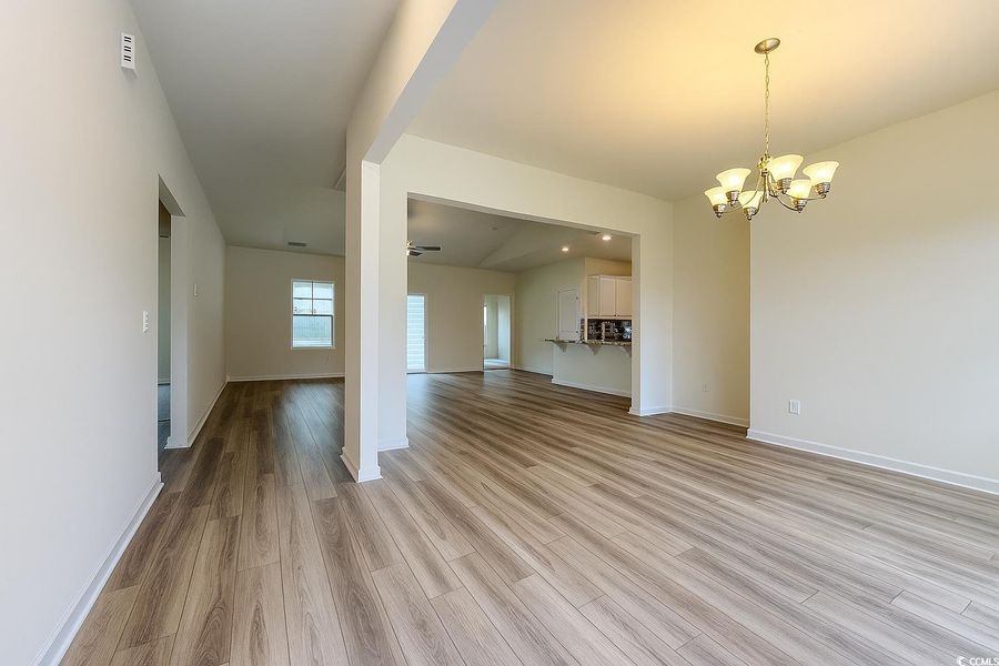 Unfurnished living room with light wood finished floors, a chandelier, ceiling fan, and lofted ceiling