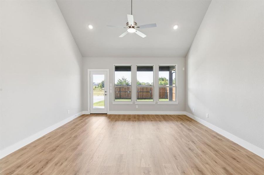 Spare room featuring light wood-style flooring, ceiling fan, high vaulted ceiling, and recessed lighting