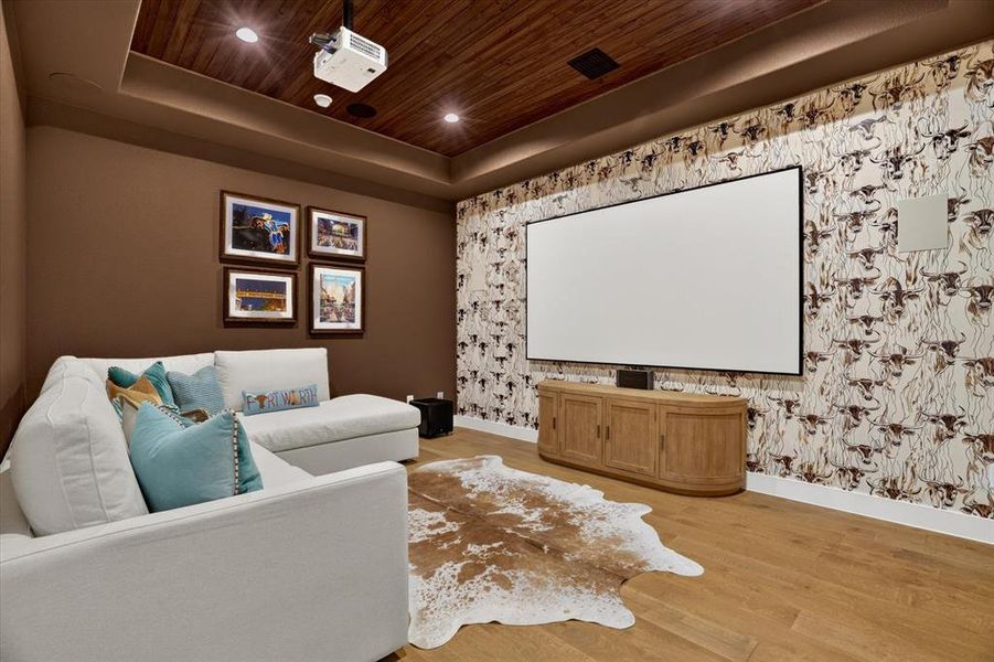 Dedicated media room featuring wood-finish flooring, a projector system, built-in screen, and a rich wood plank ceiling Dedicated media room featuring wood-finish flooring, a projector system, built-in screen, and a rich wood plank ceiling