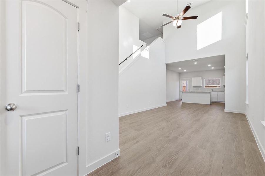 Open-concept living space featuring high ceilings, wood-finish flooring, a ceiling fan, and recessed lighting Open-concept living space featuring high ceilings, wood-finish flooring, a ceiling fan, and recessed lighting