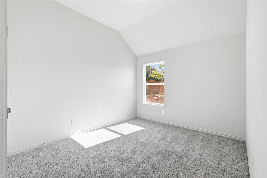 Carpeted spare room featuring lofted ceiling and baseboards
