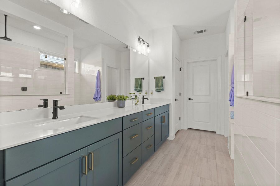 Bathroom featuring double vanity and tiled shower
