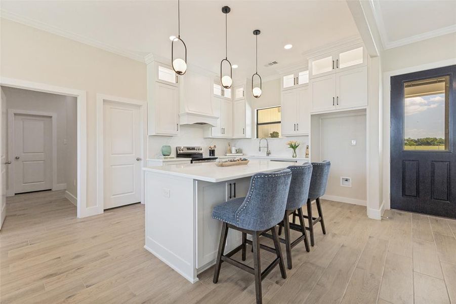 Kitchen featuring a central island with countertop seating, white shaker cabinetry, pendant lighting, and wood-finish flooring