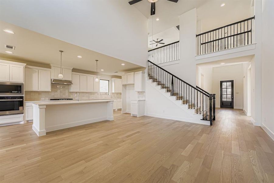 Kitchen with white cabinets, tasteful backsplash, pendant lighting, an island with sink, and recessed lighting Kitchen with white cabinets, tasteful backsplash, pendant lighting, an island with sink, and recessed lighting