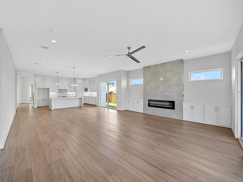 living room featuring ceiling fan, light hardwood / wood-style floors, and a tile fireplace