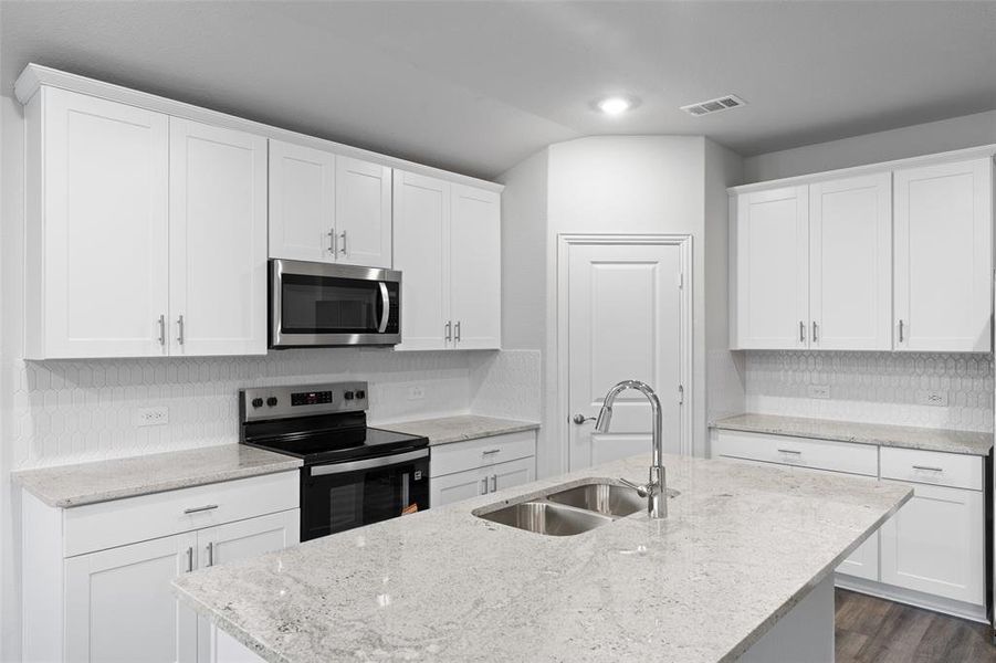 Kitchen with appliances with stainless steel finishes, tasteful backsplash, an island with sink, white cabinetry, and recessed lighting Kitchen with appliances with stainless steel finishes, tasteful backsplash, an island with sink, white cabinetry, and recessed lighting