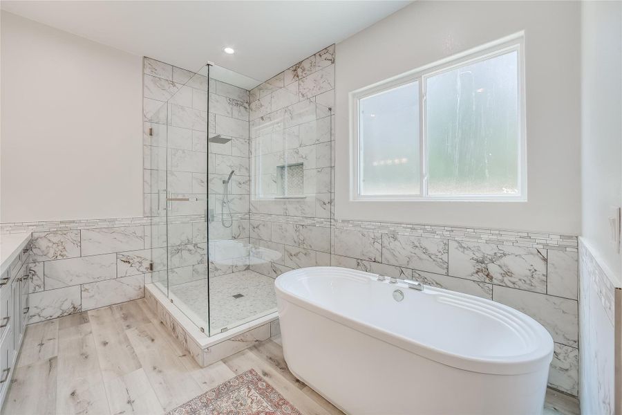 Bathroom with tile walls, independent shower and bath, and hardwood / wood-style flooring