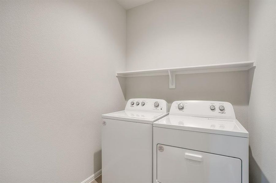 Washroom featuring washing machine and clothes dryer and a textured wall