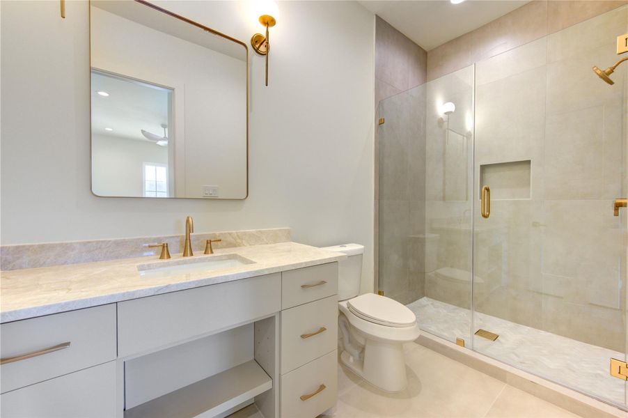 Elegant brass fixtures, modern lighting, and clean architectural lines complement the luxurious finishes, while the tub and shower combination offers versatility for guests or family members. Thoughtfully curated materials and timeless design elements transform this secondary bathroom into a stylish retreat that feels every bit as impressive as the home's primary living spaces.