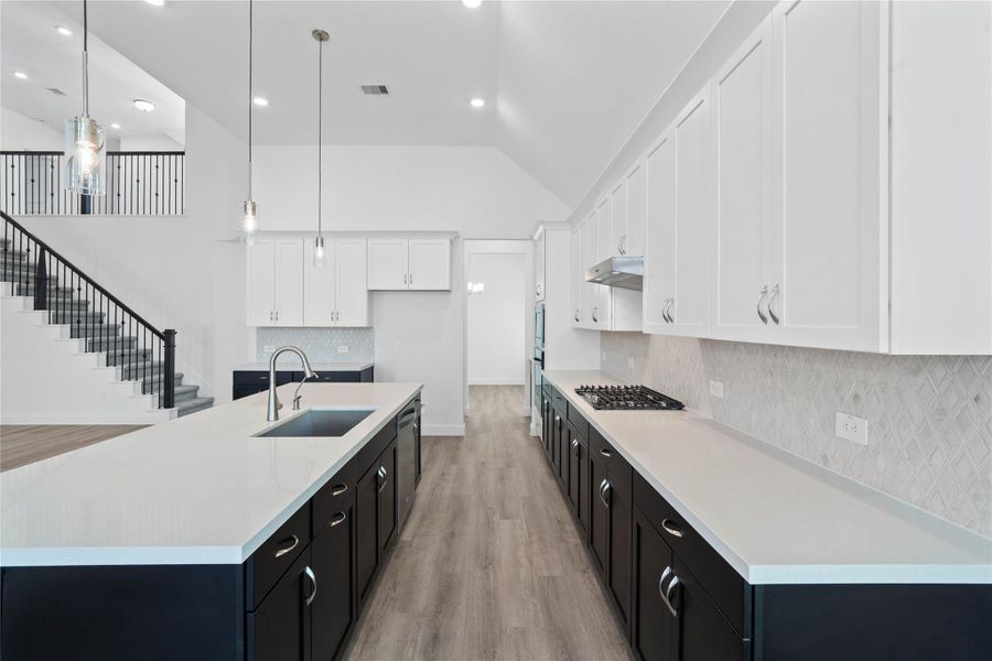 This gourmet kitchen features a modern tuxedo-style design, pairing sleek matte black base cabinets with crisp white uppers. The transitional space is anchored by a sprawling center island topped with premium quartz countertops, offering an expansive prep area and integrated stainless steel undermount sink.