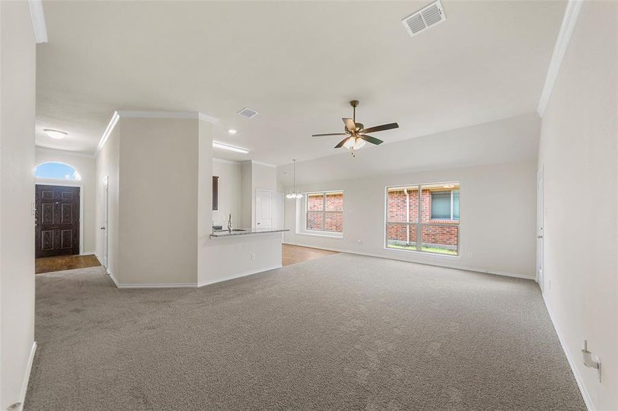 Unfurnished living room featuring light colored carpet, baseboards, crown molding, ceiling fan, and recessed lighting Unfurnished living room featuring light colored carpet, baseboards, crown molding, ceiling fan, and recessed lighting