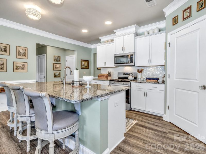 Beautiful kitchen with gray granite countertops with white cabinets and stainless steel appliances.