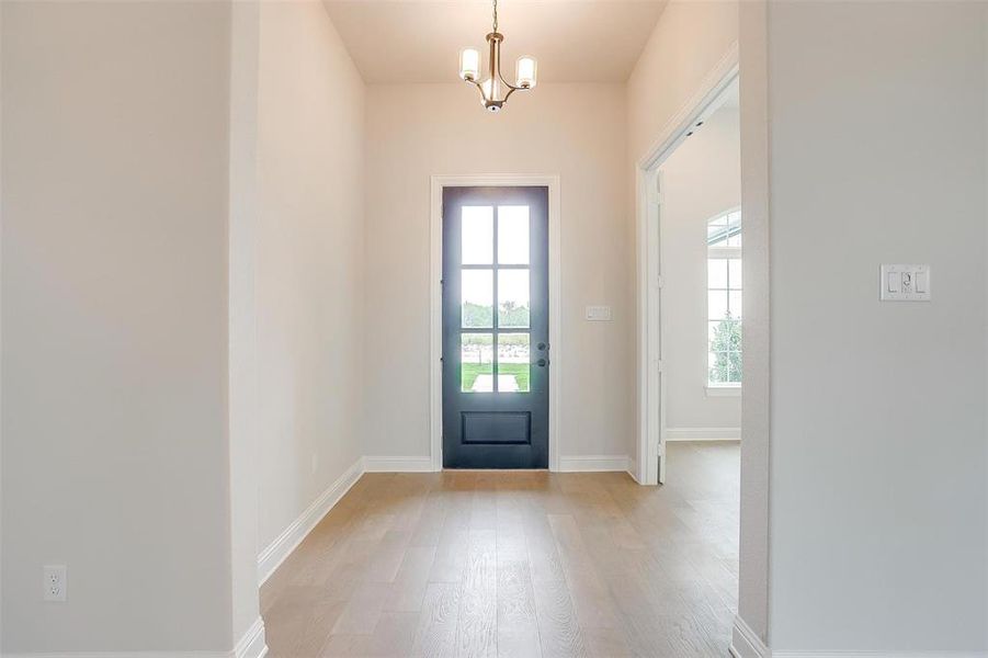 Foyer entrance with an inviting chandelier and light hardwood / wood-style floors