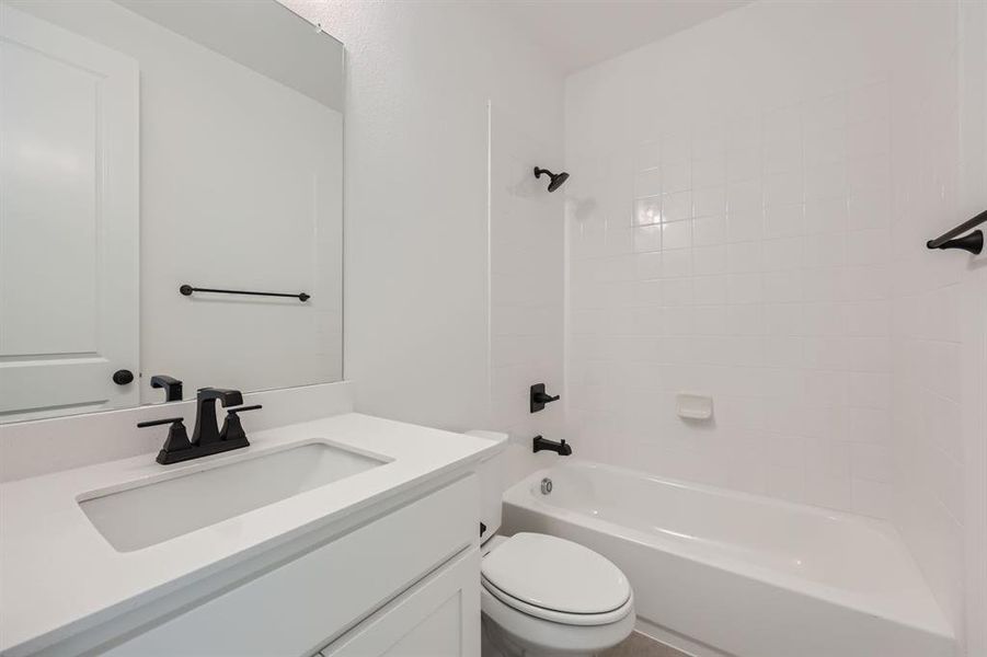 Full bathroom with vanity, tiled shower / bath combo, and toilet