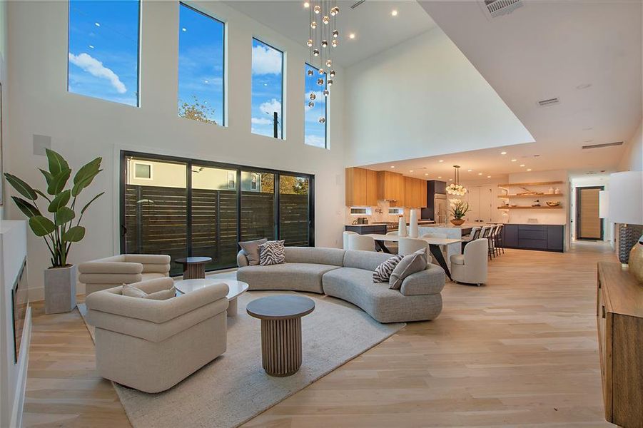 Living room with a chandelier, a high ceiling, and light hardwood / wood-style flooring