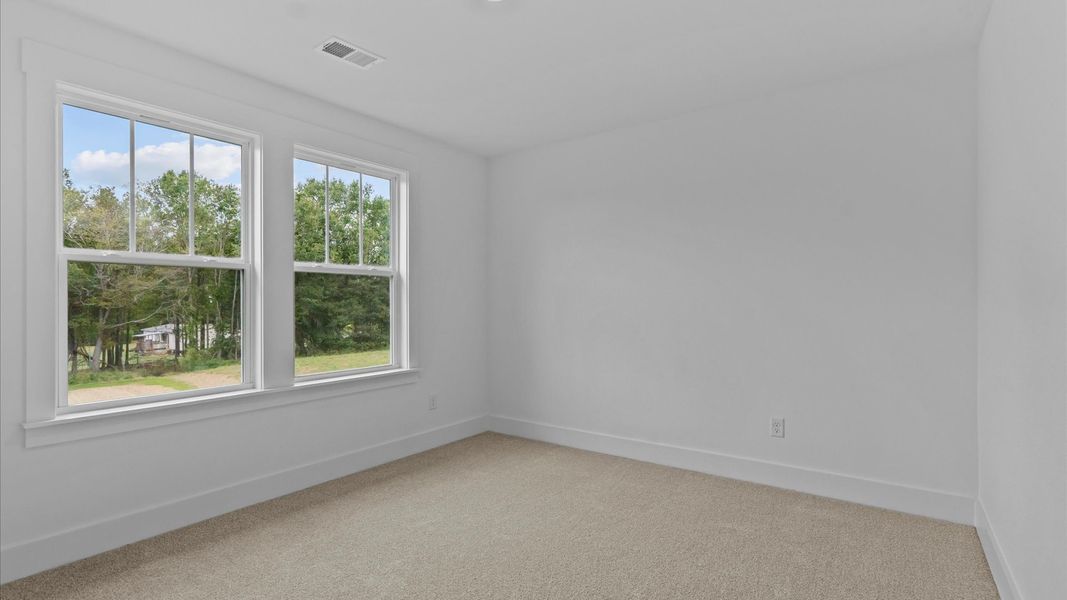 Bright and serene bedroom with comfortable carpeted flooring and large windows for vibrant light
