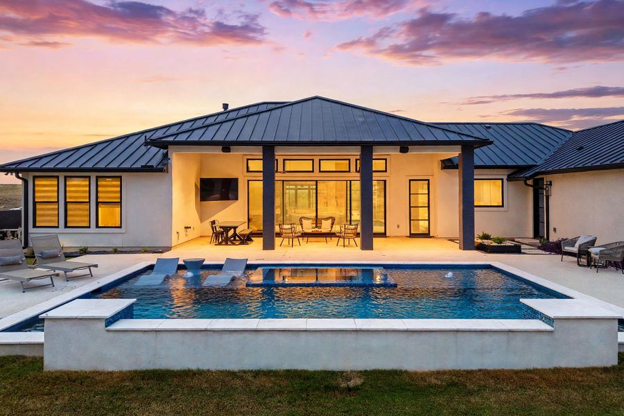 An inviting backyard oasis features a modern swimming pool against a covered back patio.
