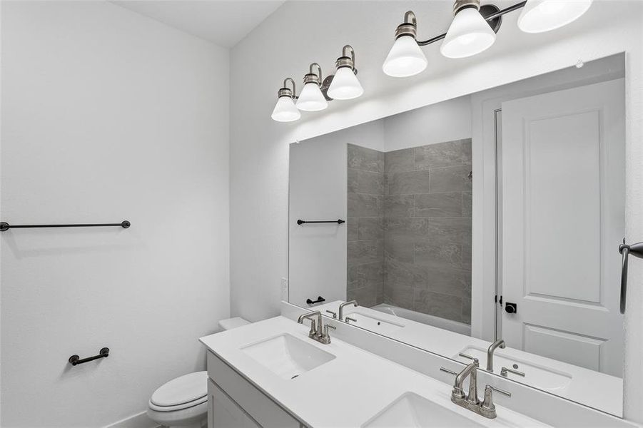 Full bathroom featuring double vanity and toilet