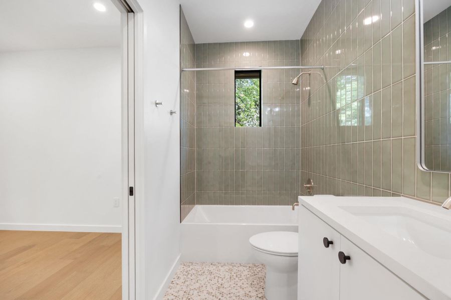 Bathroom with vanity, bathing tub / shower combination, light wood-style flooring, and recessed lighting