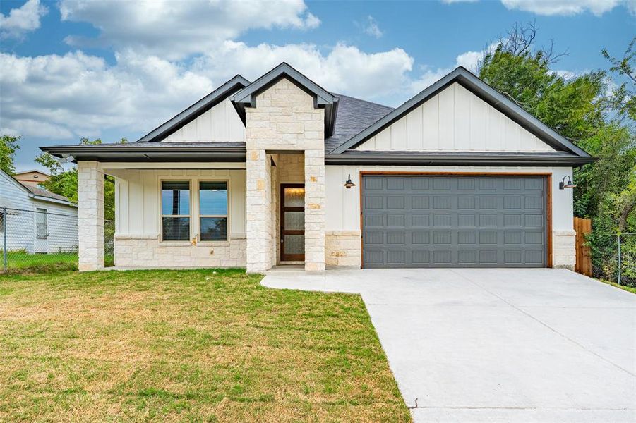 Modern farmhouse style home with board and batten siding, stone siding, and a garage