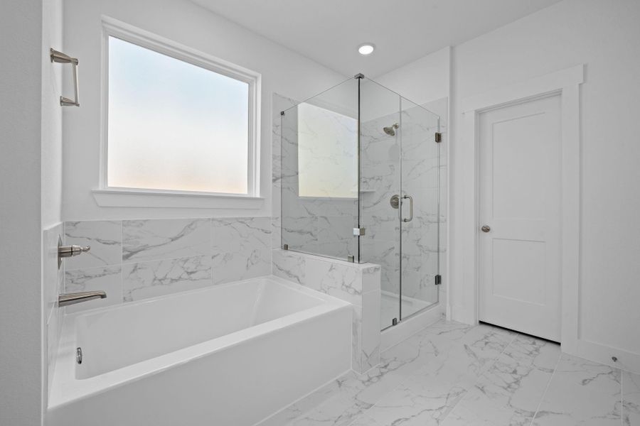 The soft glow of natural light filters through the large window, highlighting the elegant finishes – polished countertops and luxurious tile work that catches your eye and invites you to linger.