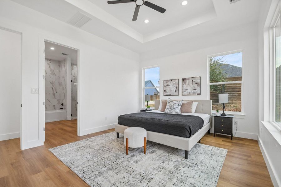 Rich wood flooring contrasts with crisp white walls and an elegant tray ceiling in this bedroom. Rich wood flooring contrasts with crisp white walls and an elegant tray ceiling in this bedroom.
