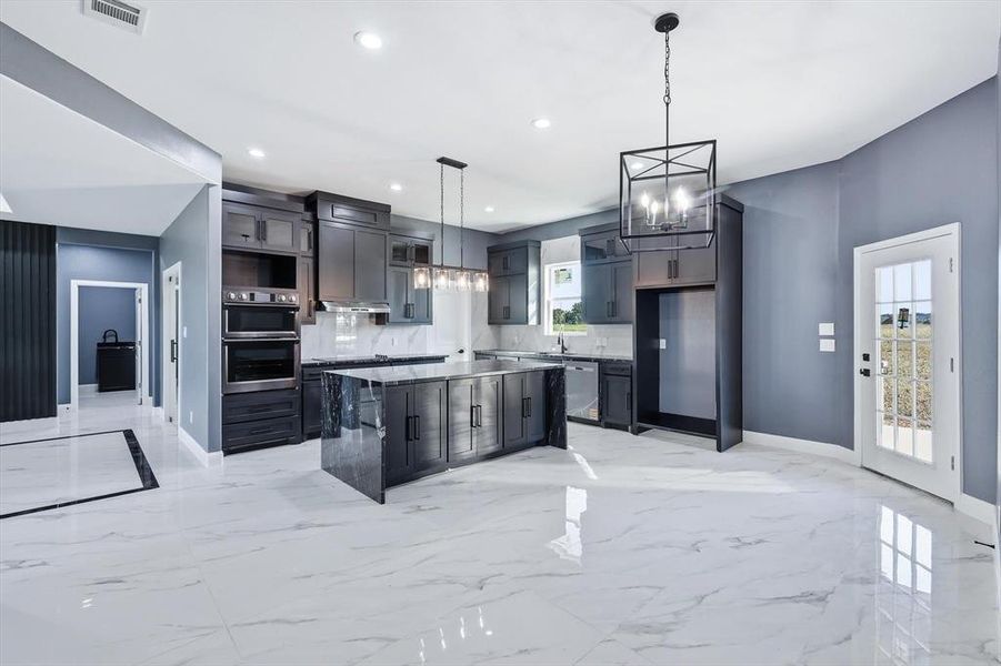Kitchen featuring light marble finish floors, a kitchen island, a chandelier, hanging light fixtures, and recessed lighting