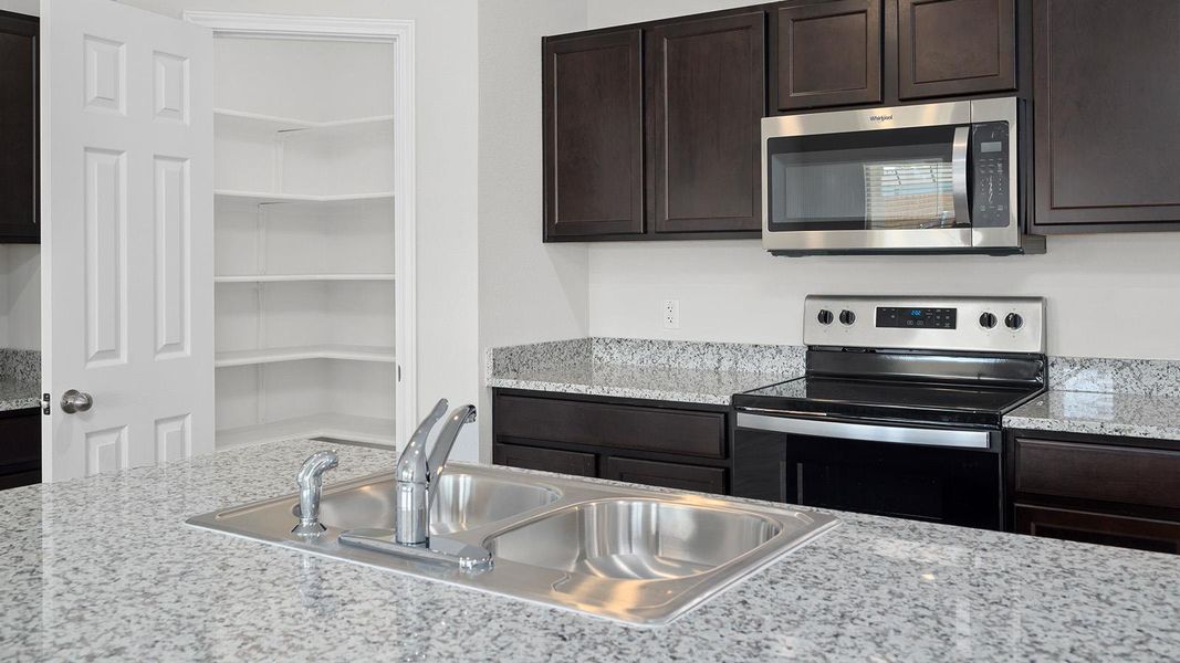 Kitchen with appliances with stainless steel finishes and dark brown cabinets