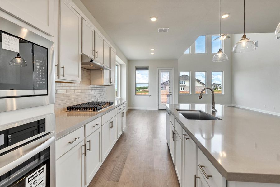 Kitchen featuring stainless steel appliances, tasteful backsplash, white cabinets, recessed lighting, and light wood-style flooring Kitchen featuring stainless steel appliances, tasteful backsplash, white cabinets, recessed lighting, and light wood-style flooring