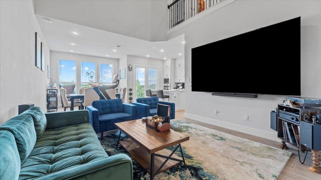 Living room with light wood-style flooring, recessed lighting, and a towering ceiling Living room with light wood-style flooring, recessed lighting, and a towering ceiling