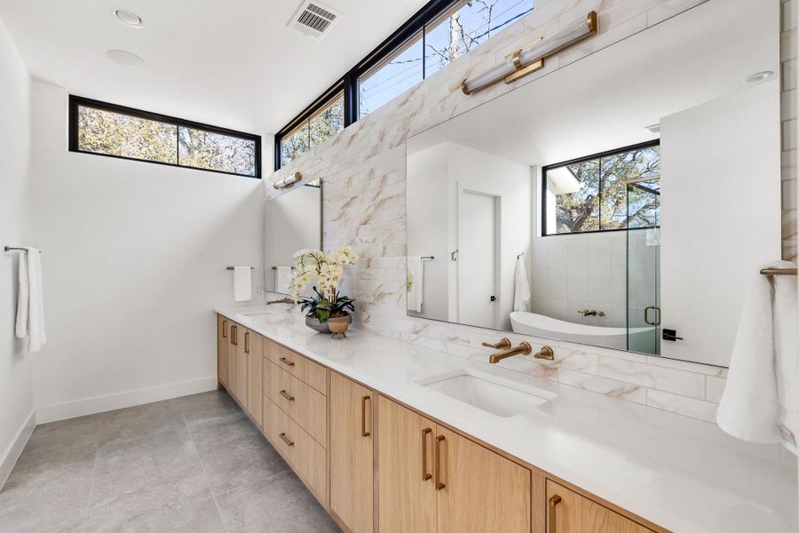 Bathroom featuring double vanity, a freestanding bath, healthy amount of natural light, and a shower with door