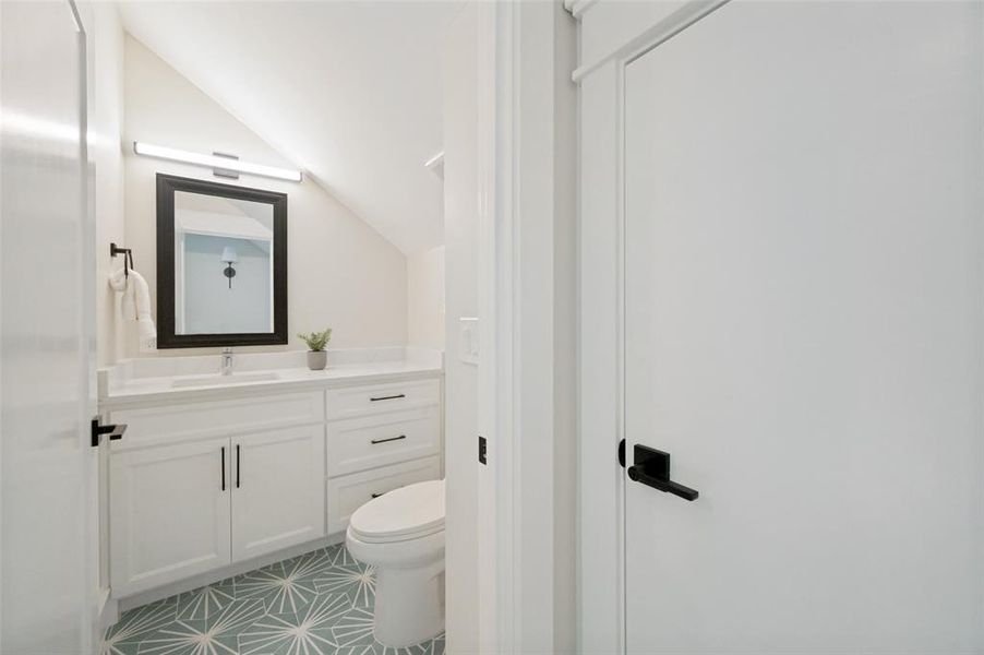 Bathroom featuring a white vanity with integrated sink, a rectangular mirror, and a geometric pattern floor tile