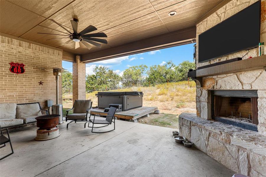 View of patio with an outdoor stone fireplace and ceiling fan