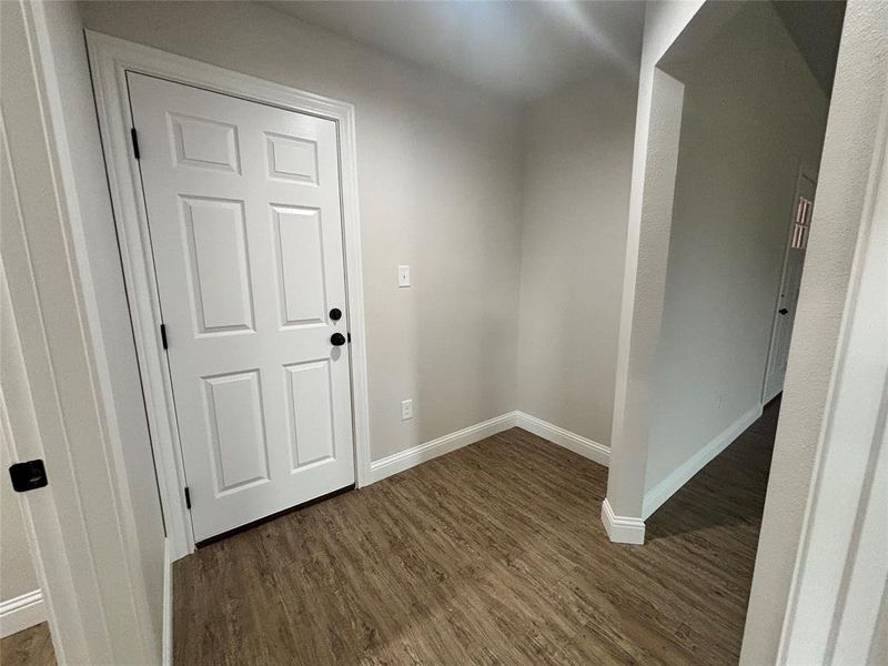 Foyer with dark wood-style flooring and baseboards
