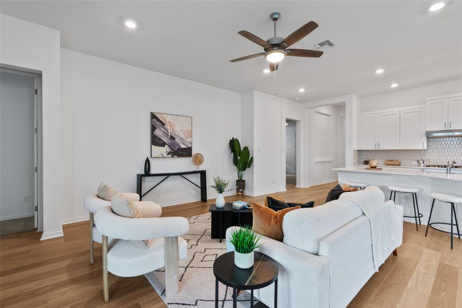 An inviting open-concept living space features light wood type flooring and a kitchen island with seating.