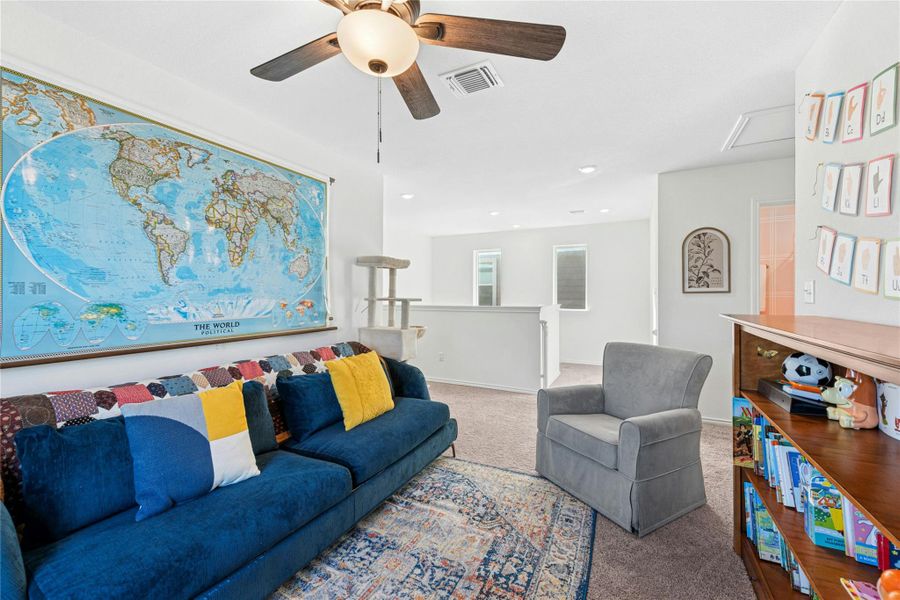 Upstairs, a spacious carpeted playroom offers a comfortable retreat, featuring recessed lighting and a ceiling fan for added comfort.