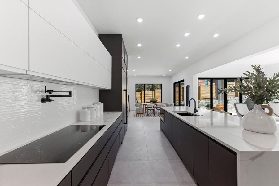 Kitchen featuring modern cabinets, black electric stovetop, recessed lighting, a large island, and light stone countertops