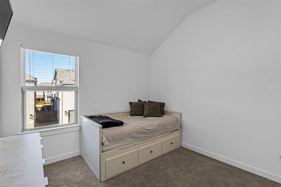 Carpeted bedroom featuring vaulted ceiling and baseboards
