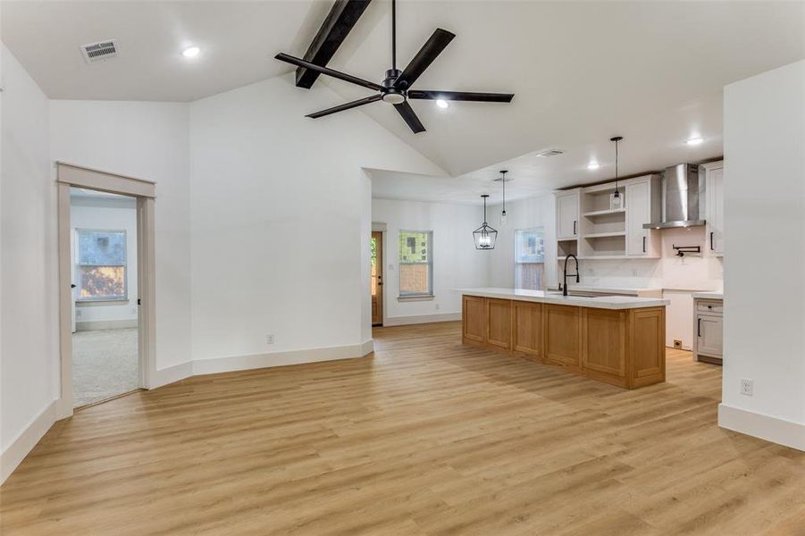 Kitchen with open shelves, beam ceiling, a kitchen island with sink, light wood-style floors, and ceiling fan Kitchen with open shelves, beam ceiling, a kitchen island with sink, light wood-style floors, and ceiling fan