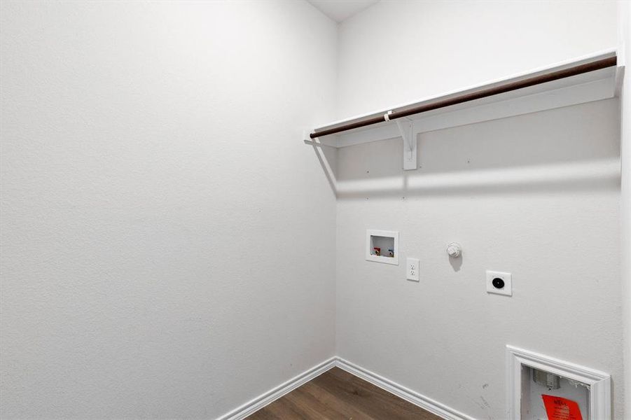 Dedicated laundry area featuring a built-in shelf, hanging rod, and wood-finish flooring