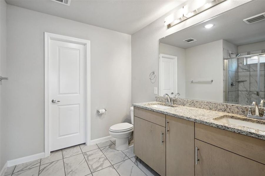 Bathroom featuring a shower with door, vanity, and toilet